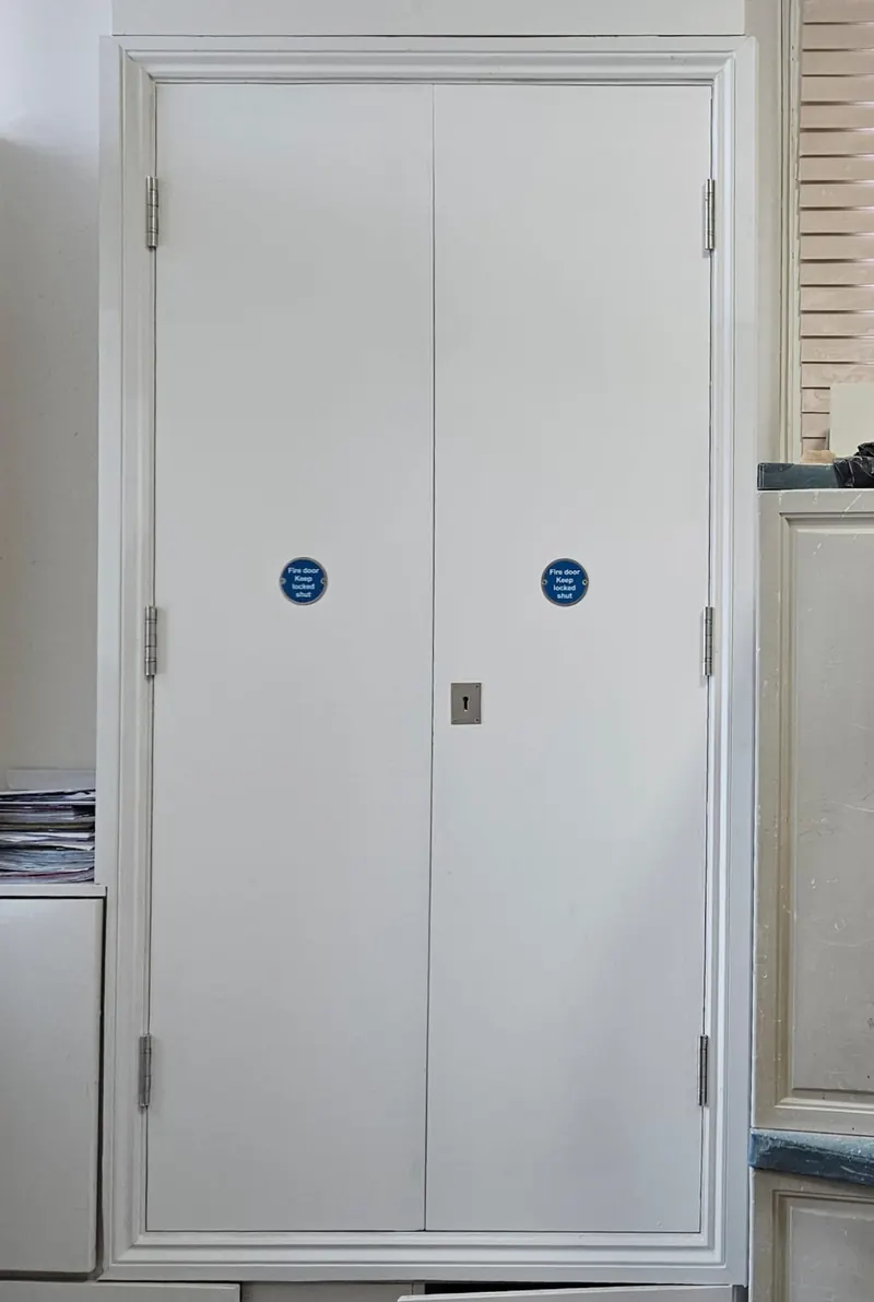 Pair of white fire doors with signage in a communal corridor